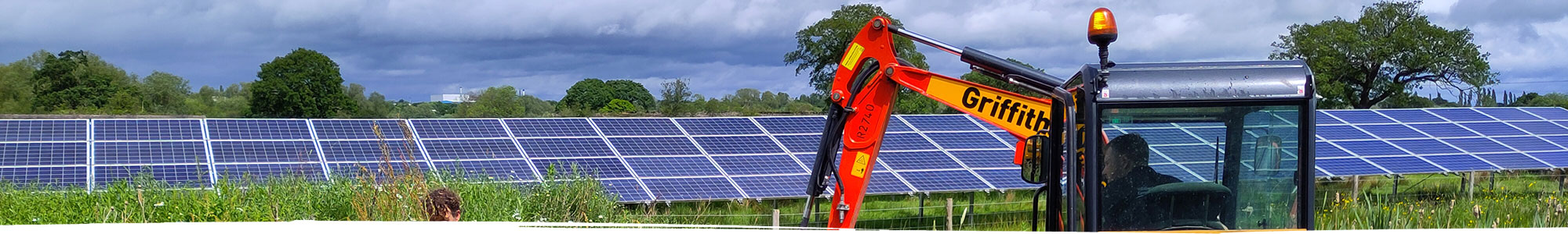 Digger working in field with solar panels