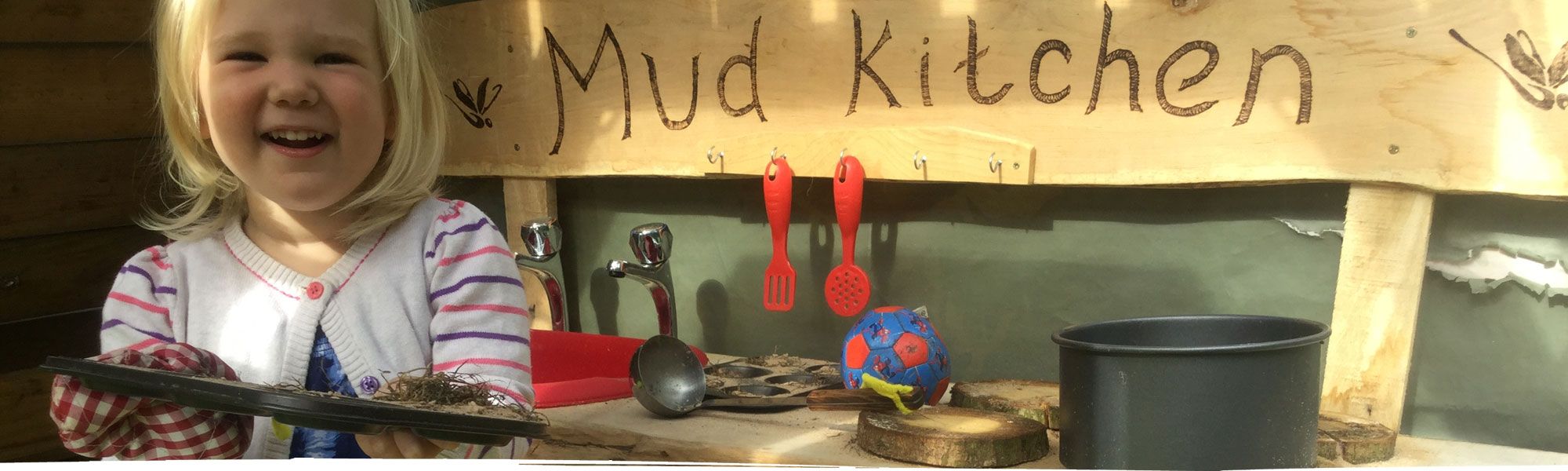 Happy girl using mud kitchen in Wrexham