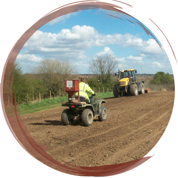 Using a tractor and a specially adapted quadbike to harrow and sow seeds to create a wildflower meadow