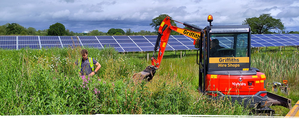 Digger working in field with solar panels