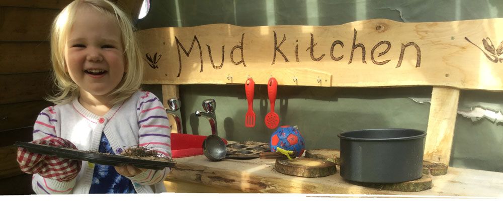 Happy girl using mud kitchen in Wrexham